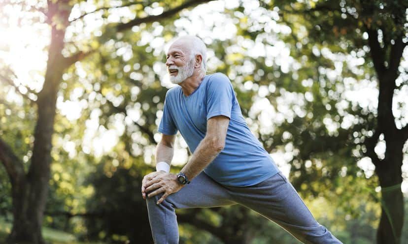 Shot of a senior man standing alone and stretching during his outdoor workout