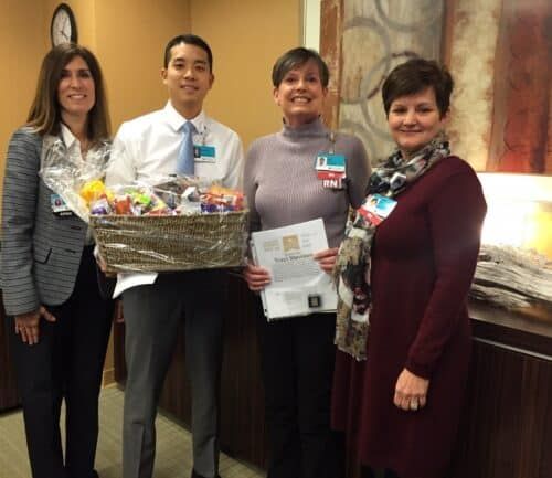 Four healthcare professionals presenting gift basket and certificate to award recipient