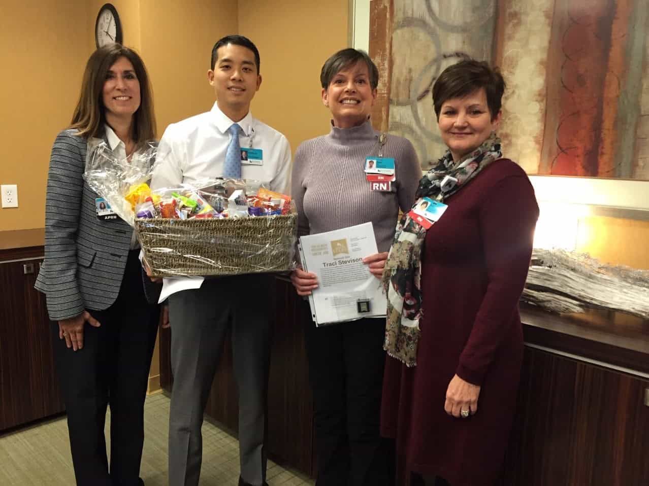 Four healthcare professionals presenting gift basket and certificate to award recipient