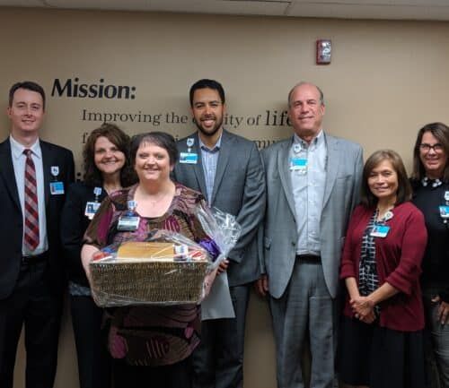 Healthcare team celebrating employee recognition with gift basket presentation ceremony