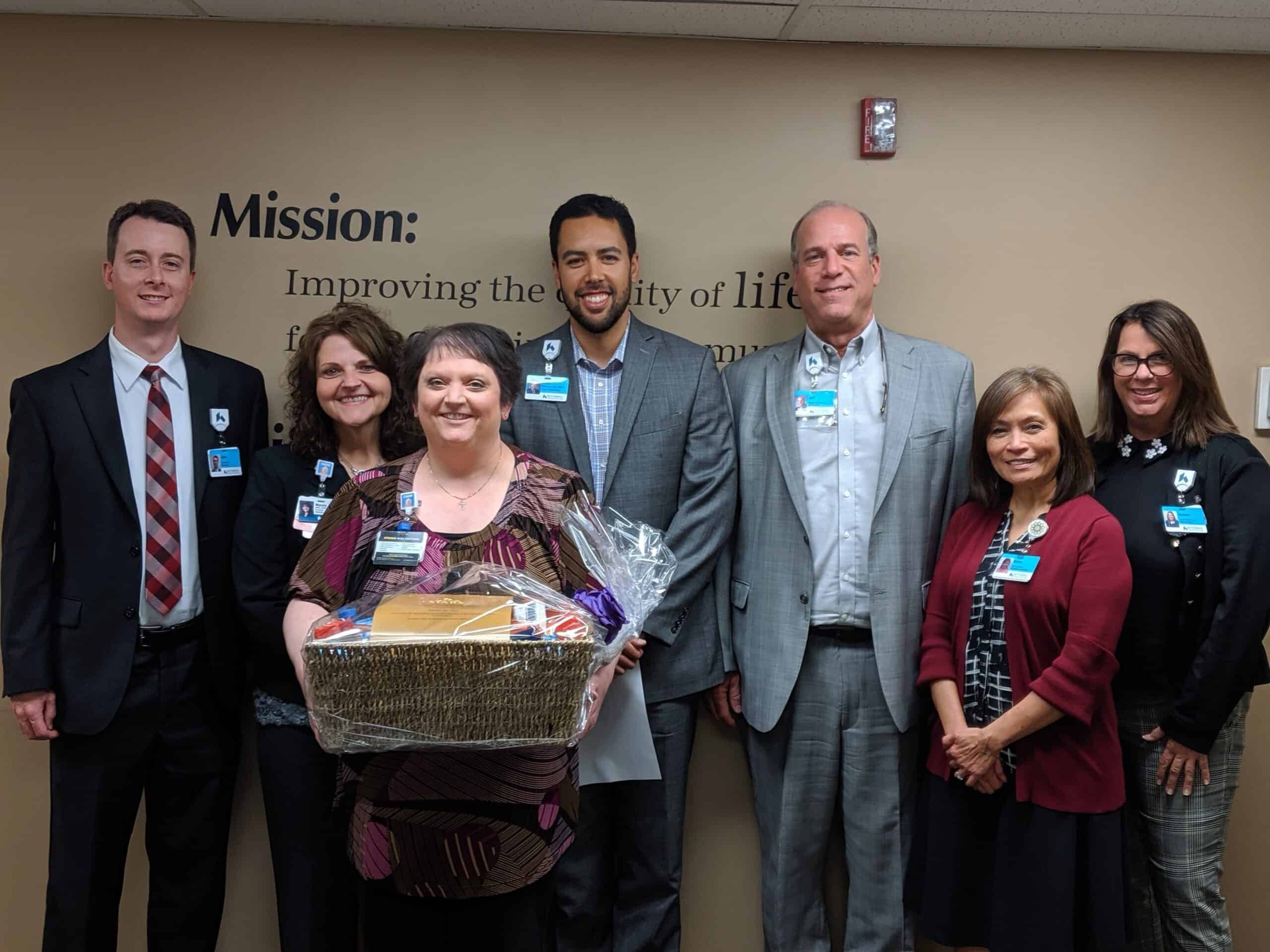 Healthcare team celebrating employee recognition with gift basket presentation ceremony