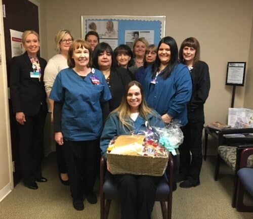 Healthcare team celebrating with gift basket presentation in medical office setting