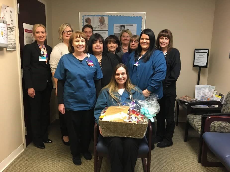 Healthcare team celebrating with gift basket presentation in medical office setting