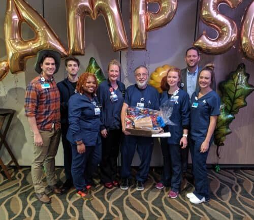 Healthcare team celebrating Employee of the Month with balloons and gift basket presentation