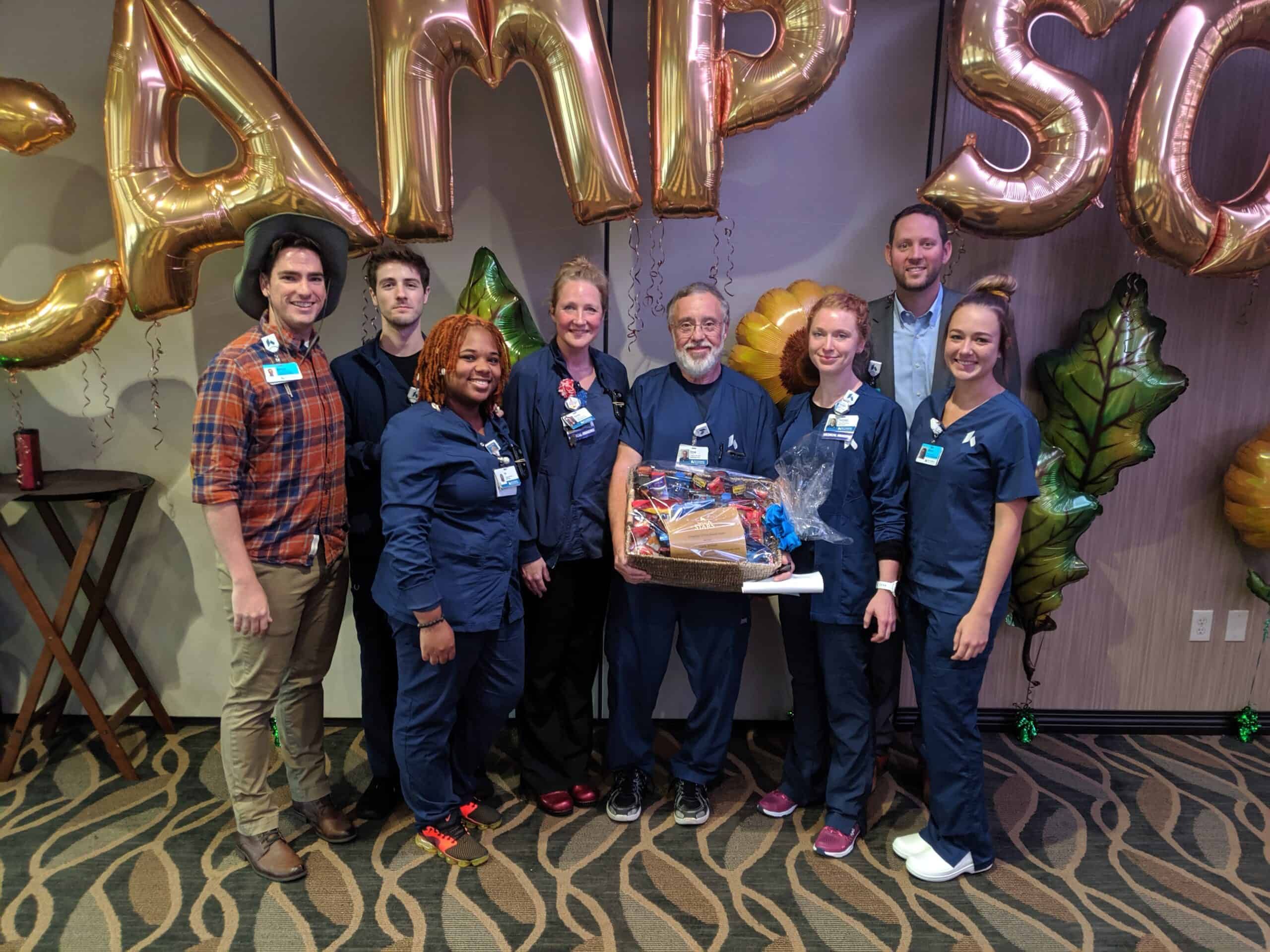 Healthcare team celebrating Employee of the Month with balloons and gift basket presentation