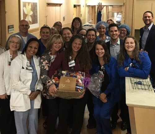 Healthcare team celebrating employee of the month with gift basket in hospital hallway
