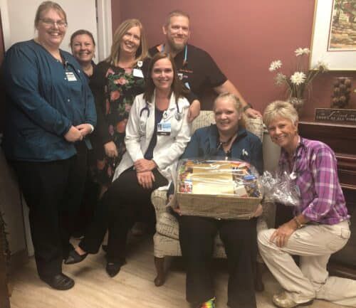 Healthcare staff presenting gift basket to seated patient in medical facility
