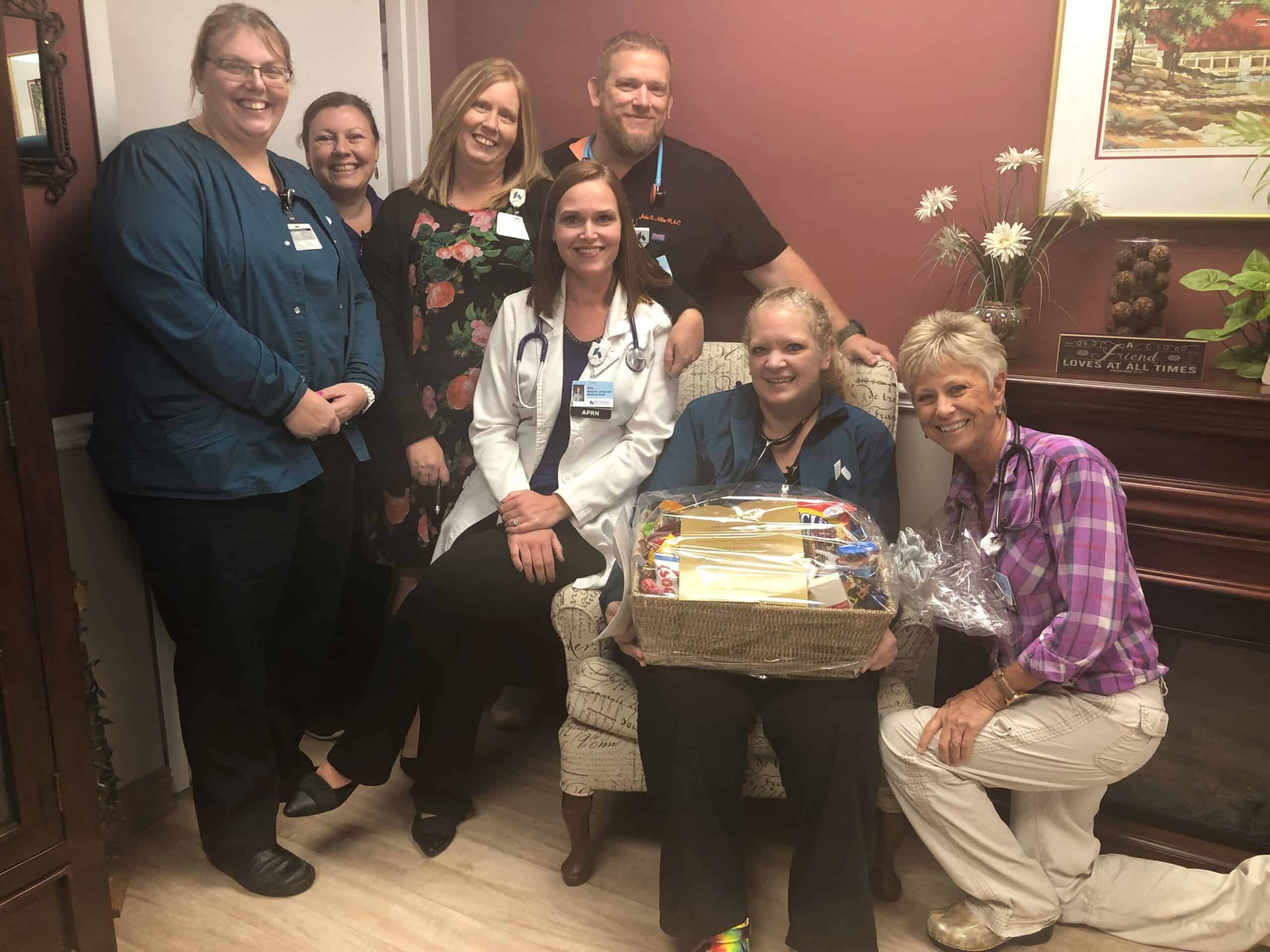 Healthcare staff presenting gift basket to seated patient in medical facility