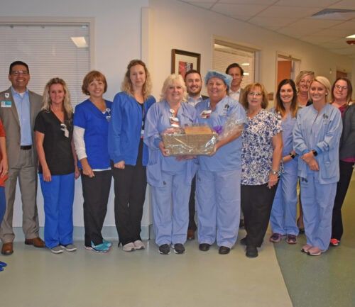 Healthcare team celebrating with gift basket presentation in hospital hallway