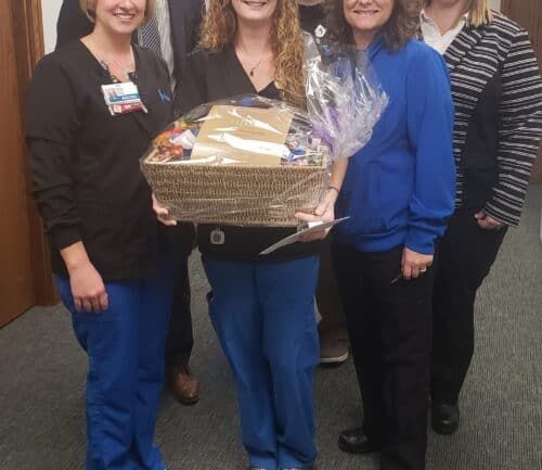 Healthcare team presenting gift basket to employee recognition award recipient