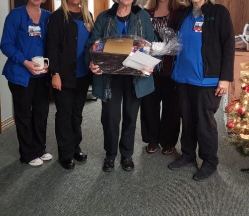 Five healthcare workers celebrating employee recognition with gift basket presentation