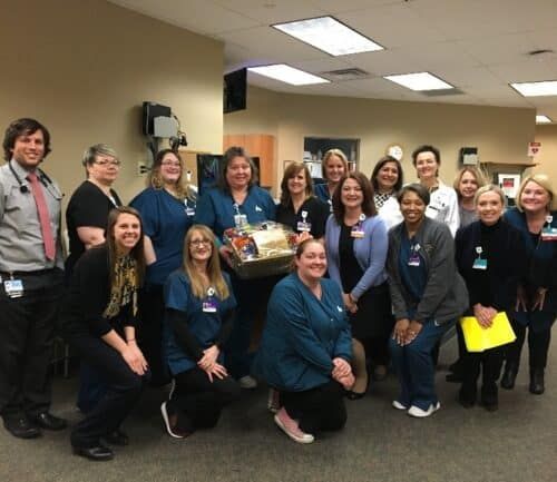 Healthcare team members posing together with gift basket in hospital setting