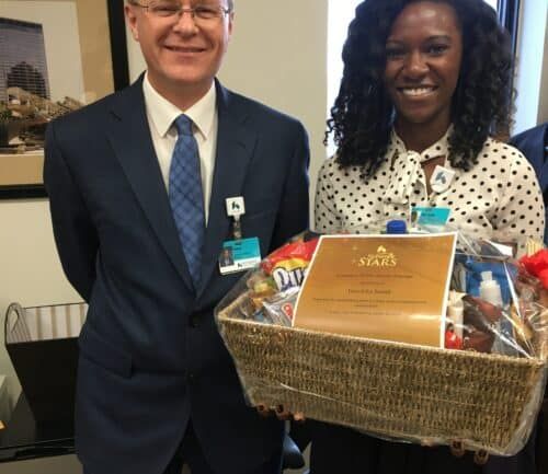 Man in suit presenting gift basket to woman in polka dot shirt