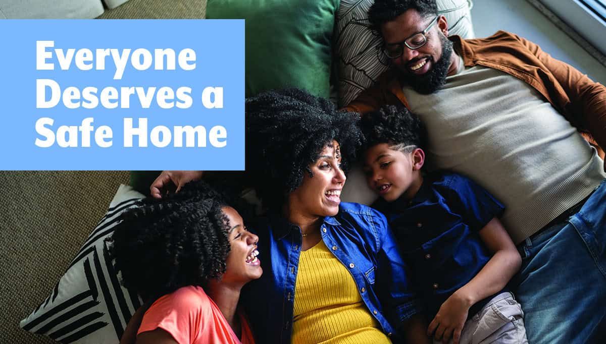 Happy family of four lying together on couch with "Everyone Deserves a Safe Home" text overlay