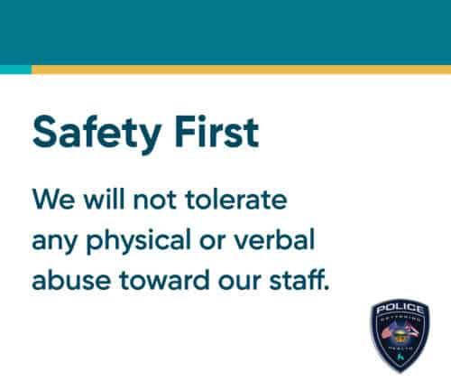 Safety First workplace policy sign stating no tolerance for staff abuse with police badge