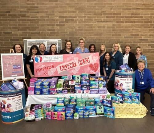 Healthcare workers standing behind table displaying donated feminine hygiene products for charity drive