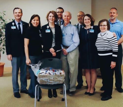 Group of Kettering Health employees posing together with gift basket in hospital lobby