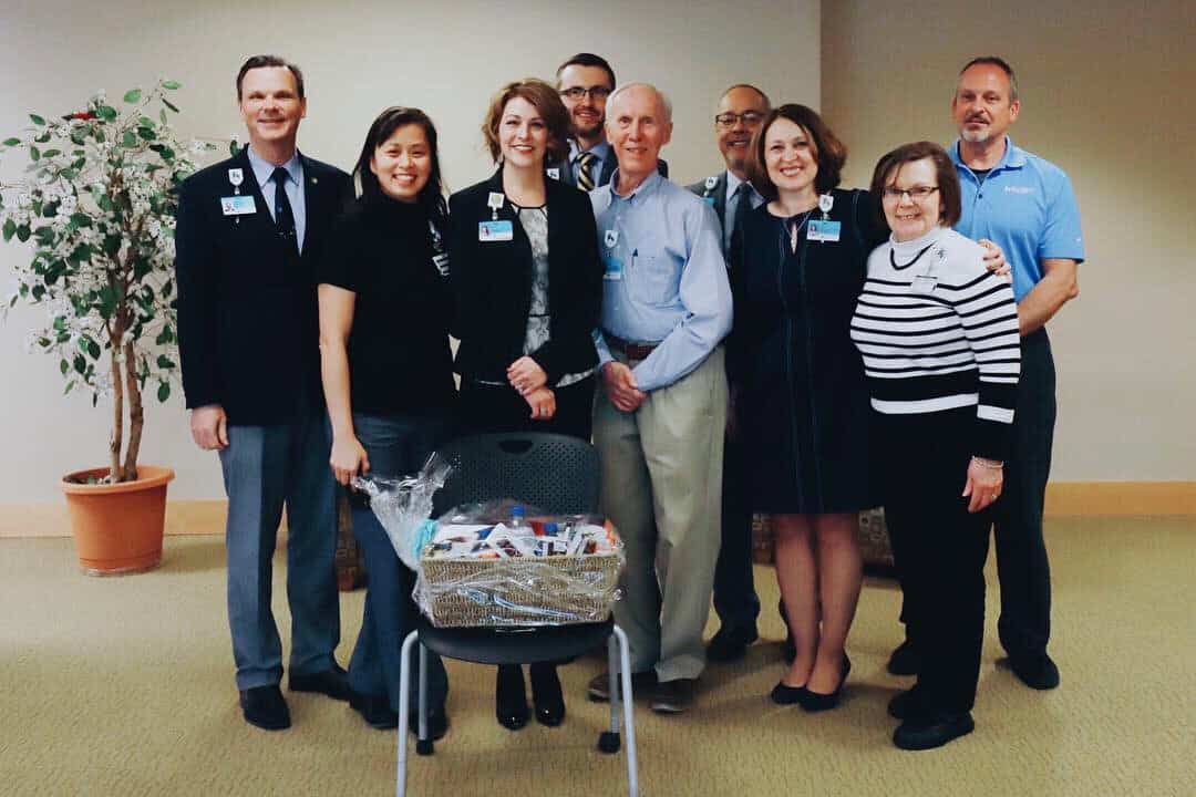 Group of Kettering Health employees posing together with gift basket in hospital lobby