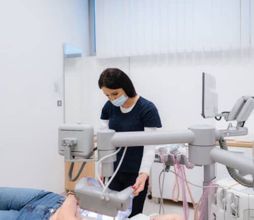 Nurse in mask preparing medical equipment for patient's breast scan procedure