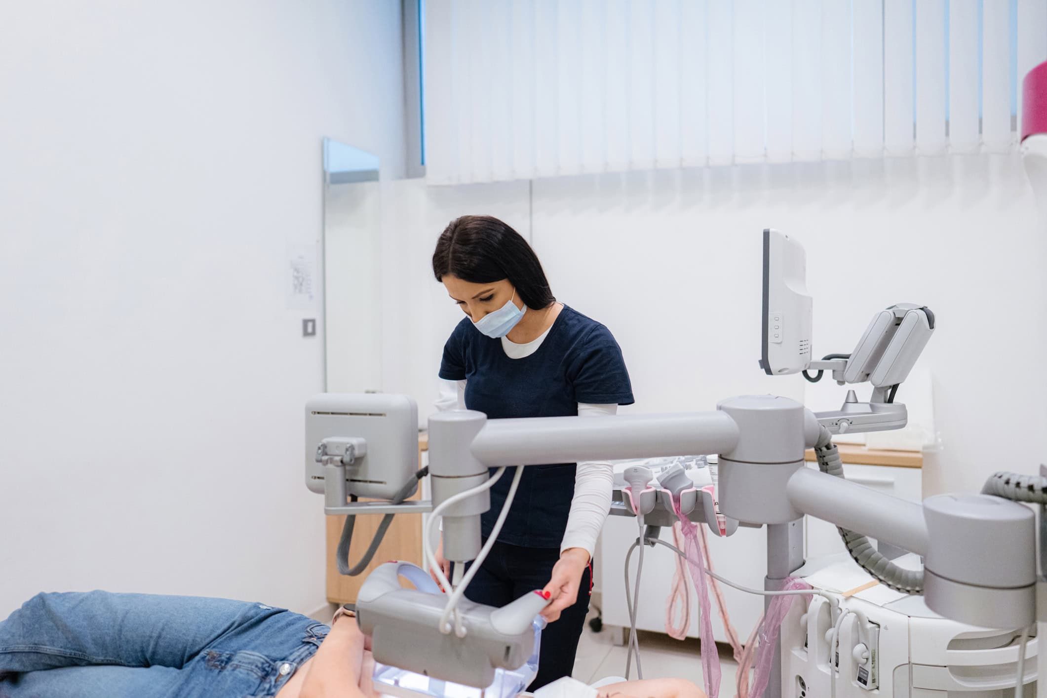 Nurse in mask preparing medical equipment for patient's breast scan procedure
