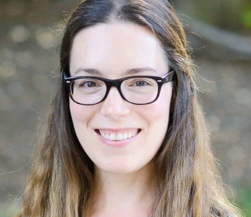 Professional headshot of Amelia Burke wearing glasses and smiling at camera