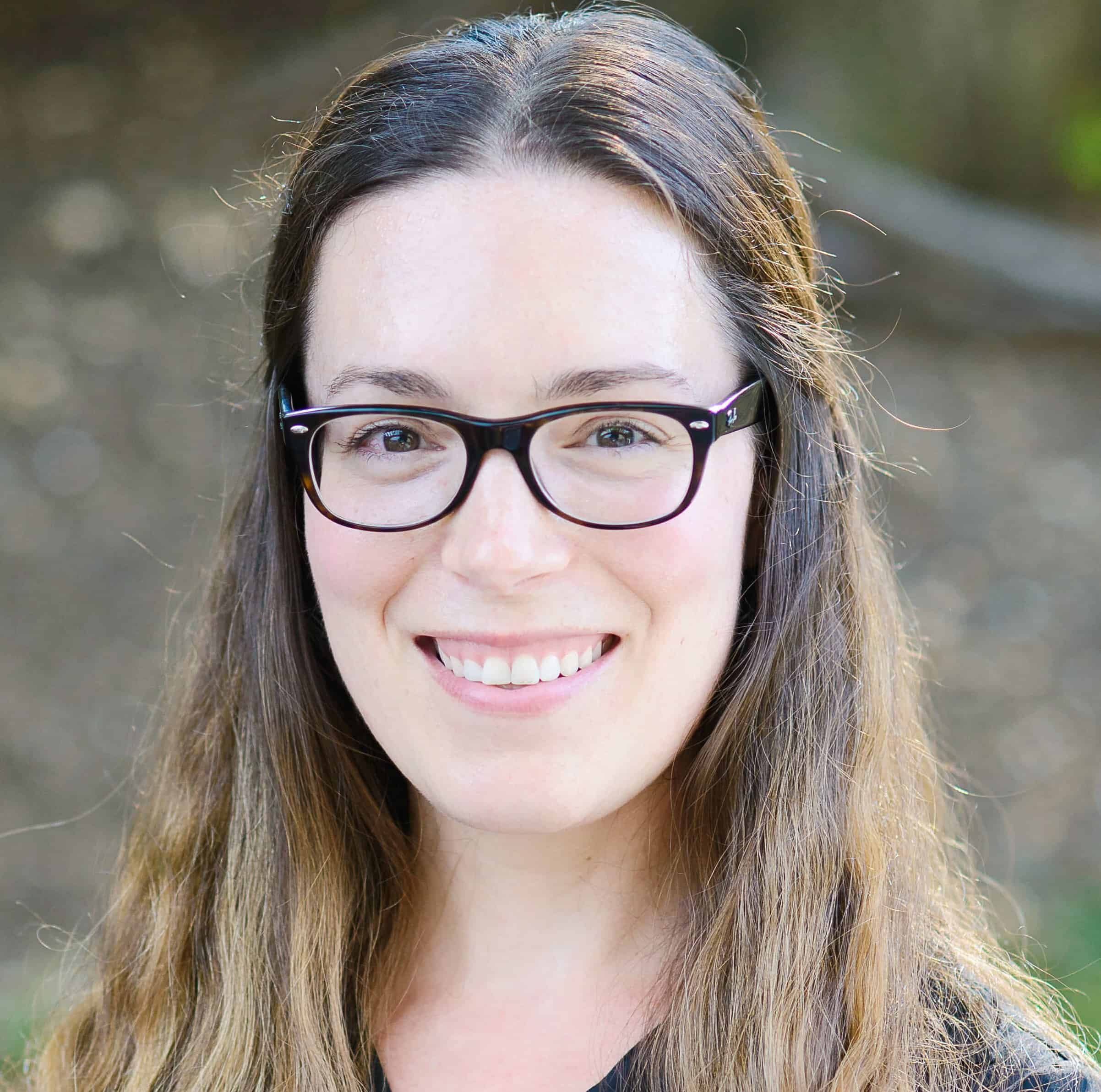 Professional headshot of Amelia Burke wearing glasses and smiling at camera