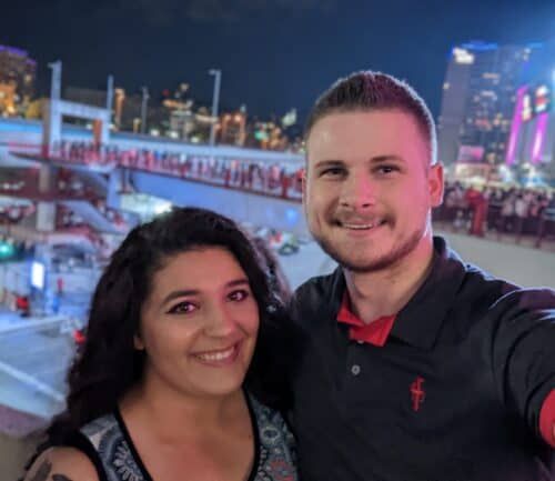 Young couple taking selfie together at nighttime outdoor ice skating rink
