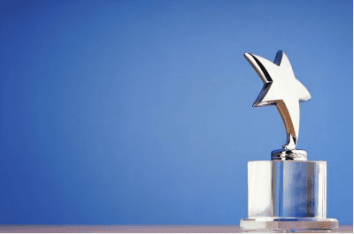 Silver star trophy award on glass base against blue background