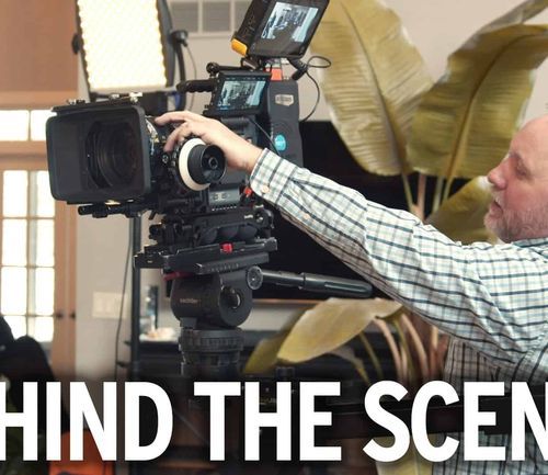 Cameraman adjusting professional video equipment during behind-the-scenes filming at healthcare facility