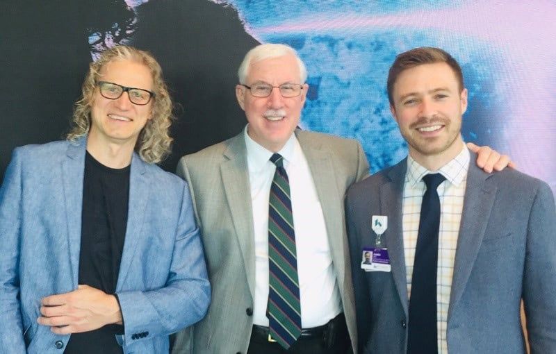 Three healthcare professionals in business attire posing together at Brain-Spine open house event.