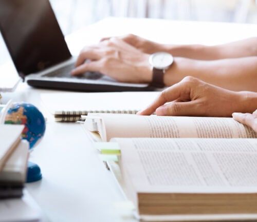 University students studying together with laptop, books, and globe on desk