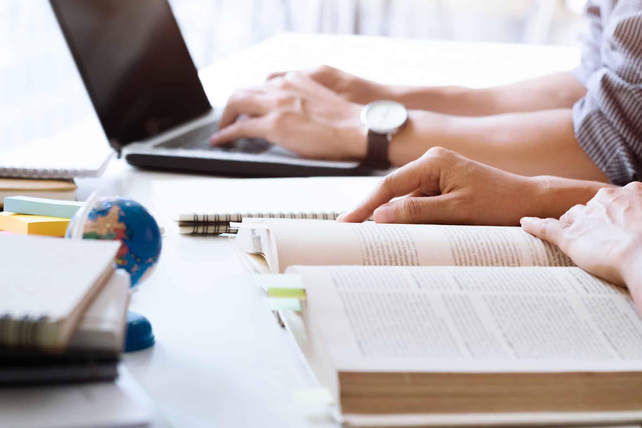 University students studying together with laptop, books, and globe on desk