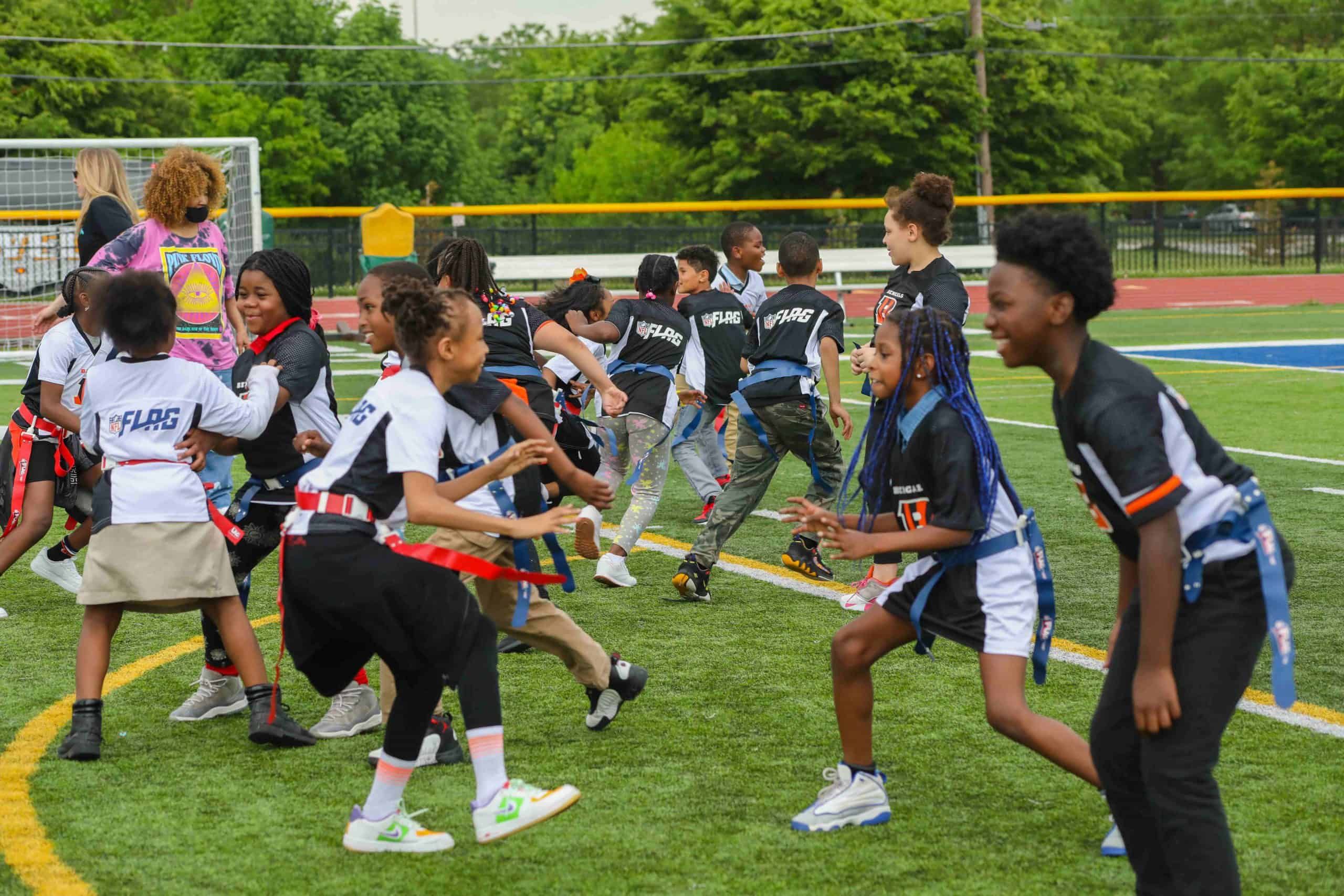 Children playing flag football on a grassy field during an outdoor sports event.