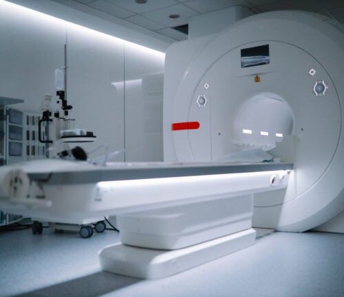 Modern CT scanner machine with patient table in sterile hospital radiology room