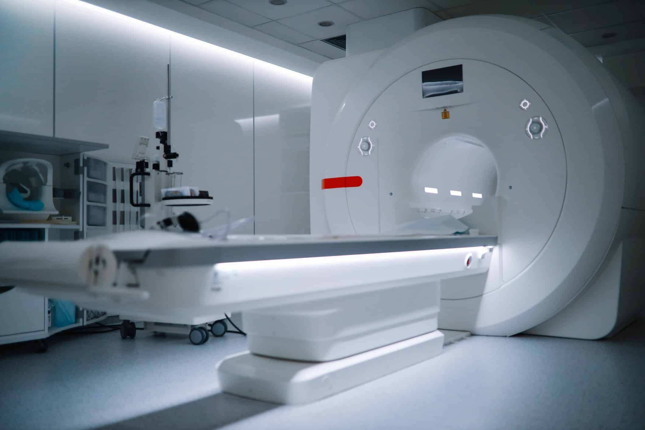 Modern CT scanner machine with patient table in sterile hospital radiology room