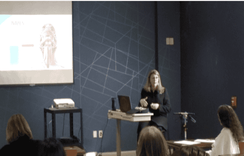 Healthcare professional presenting to audience with projection screen and laptop setup