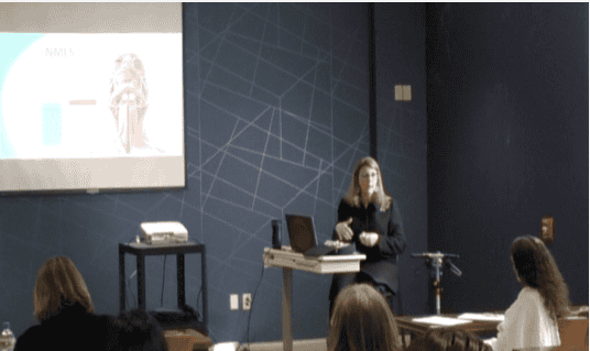 Healthcare professional presenting to audience with projection screen and laptop setup