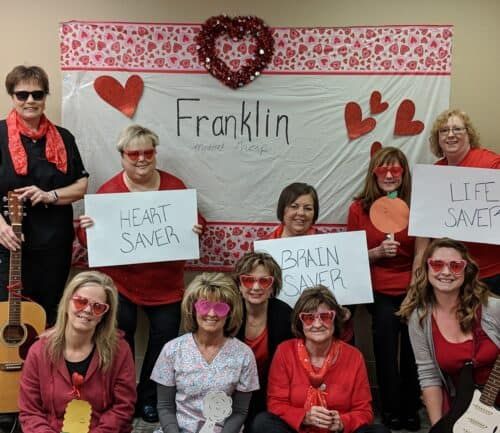 Healthcare workers celebrating Valentine's Day holding signs reading "Heart Saver," "Brain Saver," and "Life Saver"