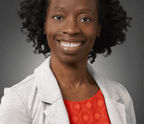 Professional headshot of Chioma Lindo wearing gray blazer and red top, smiling warmly