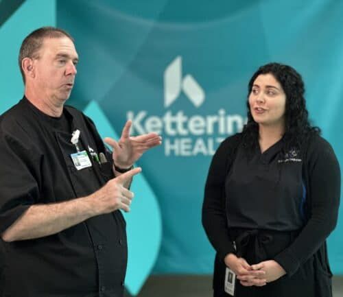 Two healthcare professionals in black uniforms discussing work at Kettering Health facility