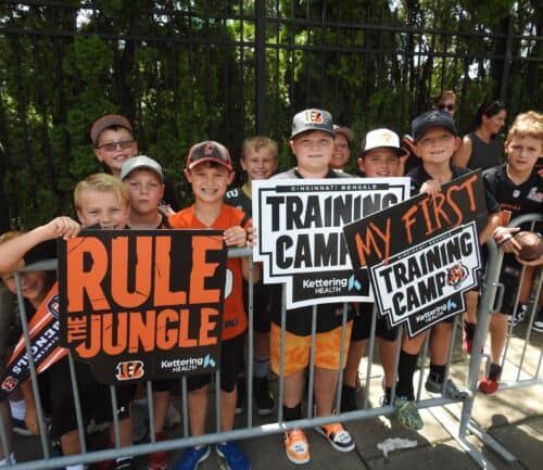 Young fans holding Cincinnati Bengals "Rule the Jungle" and "My First Training Camp" signs