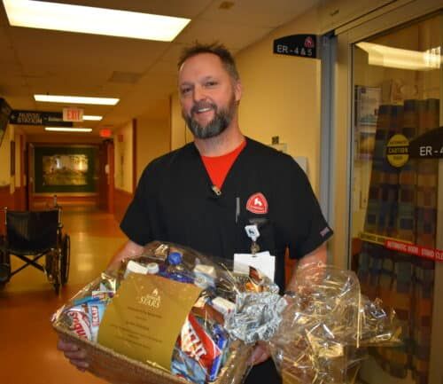 Healthcare worker holding gift baskets in hospital hallway near emergency room