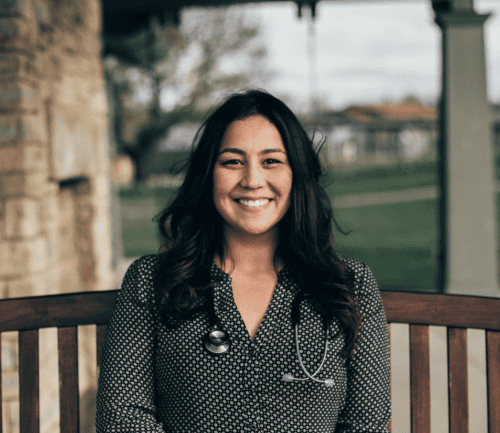 Professional headshot of healthcare provider Danielle wearing stethoscope and polka dot top, smiling outdoors