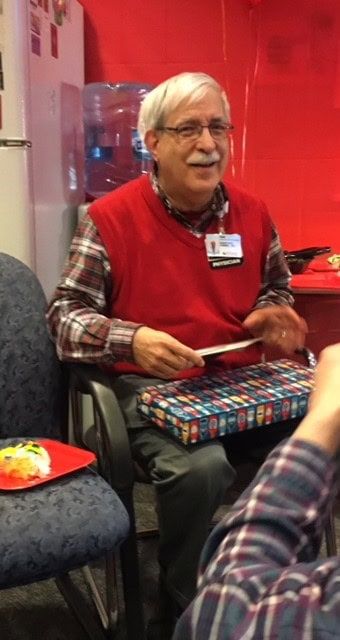 Doctor in red vest and glasses reading to patients in healthcare waiting area