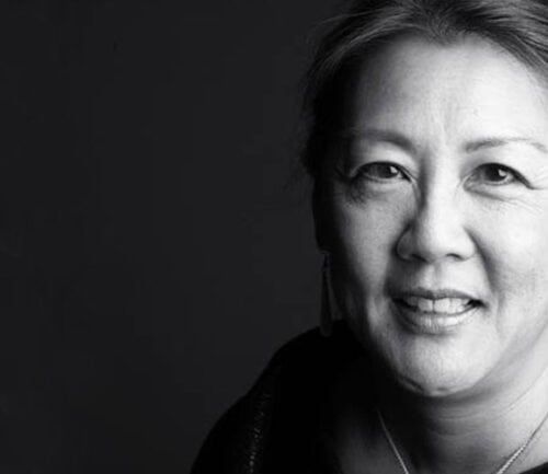 Professional headshot of Dr. Mau smiling against dark background in black and white