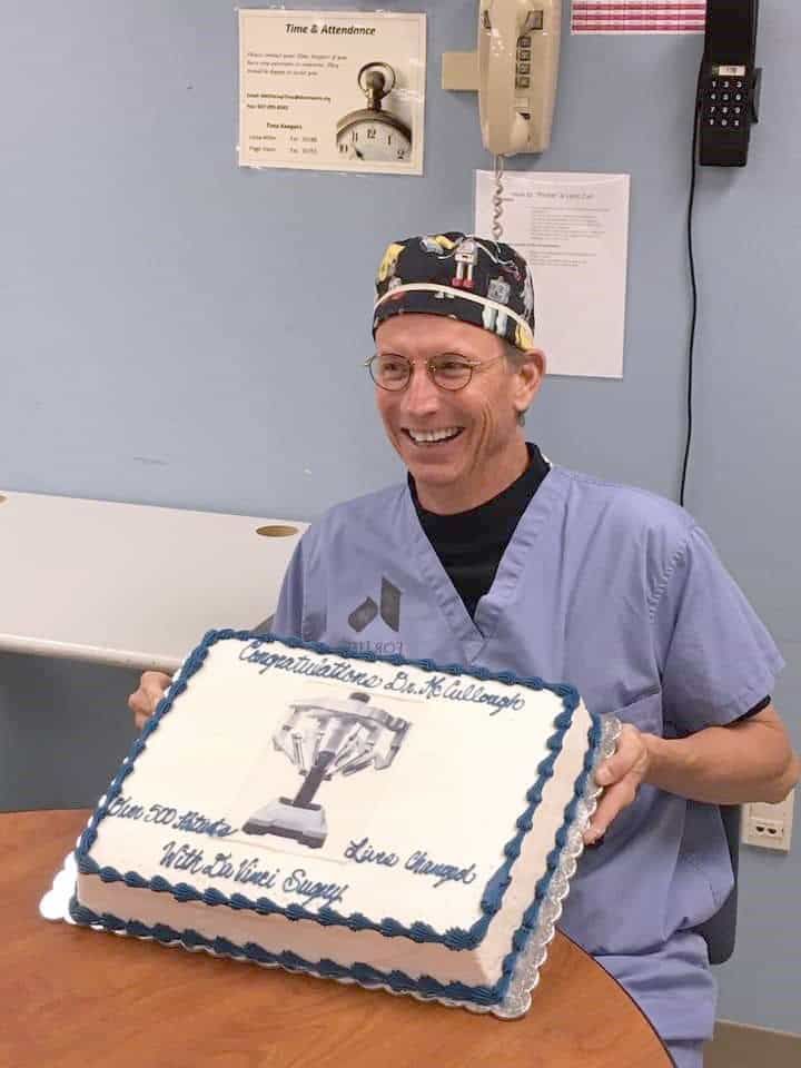 Doctor in scrubs holding congratulatory cake celebrating milestone achievement at Kettering Health