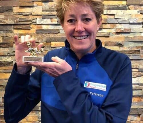 Dr. Peterson holding a small trophy or award while smiling at camera