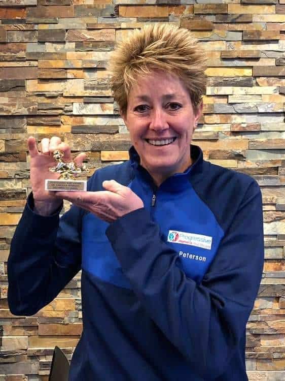 Dr. Peterson holding a small trophy or award while smiling at camera