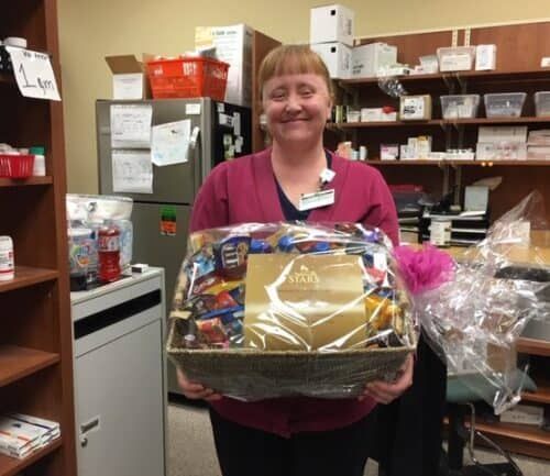 Healthcare employee holding gift basket in pharmacy storage room