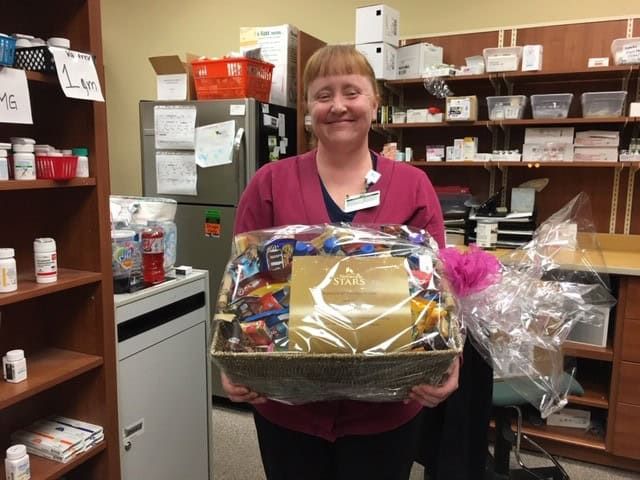Healthcare employee holding gift basket in pharmacy storage room